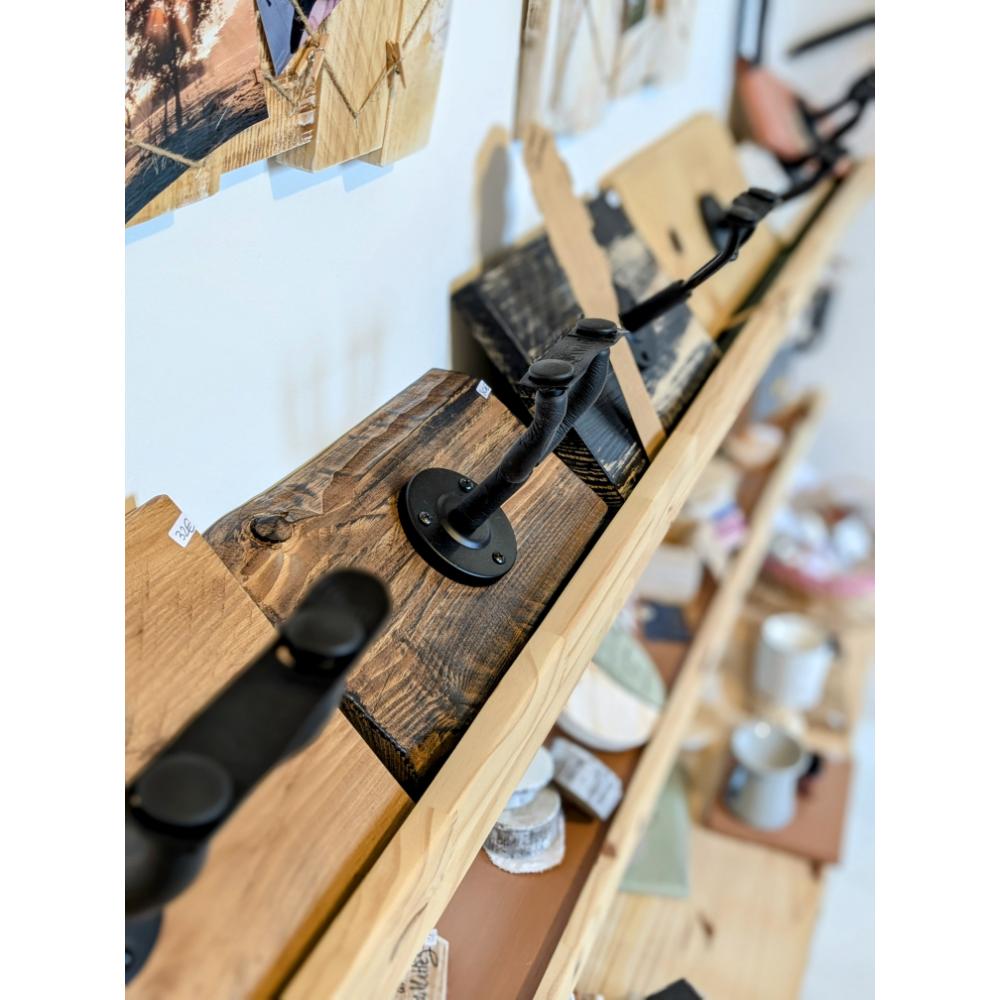 Étagère en bois avec crochets métalliques noirs.