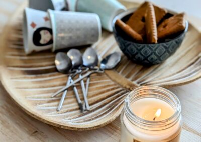 Bougies allumées, tasses et biscuits sur plateau.