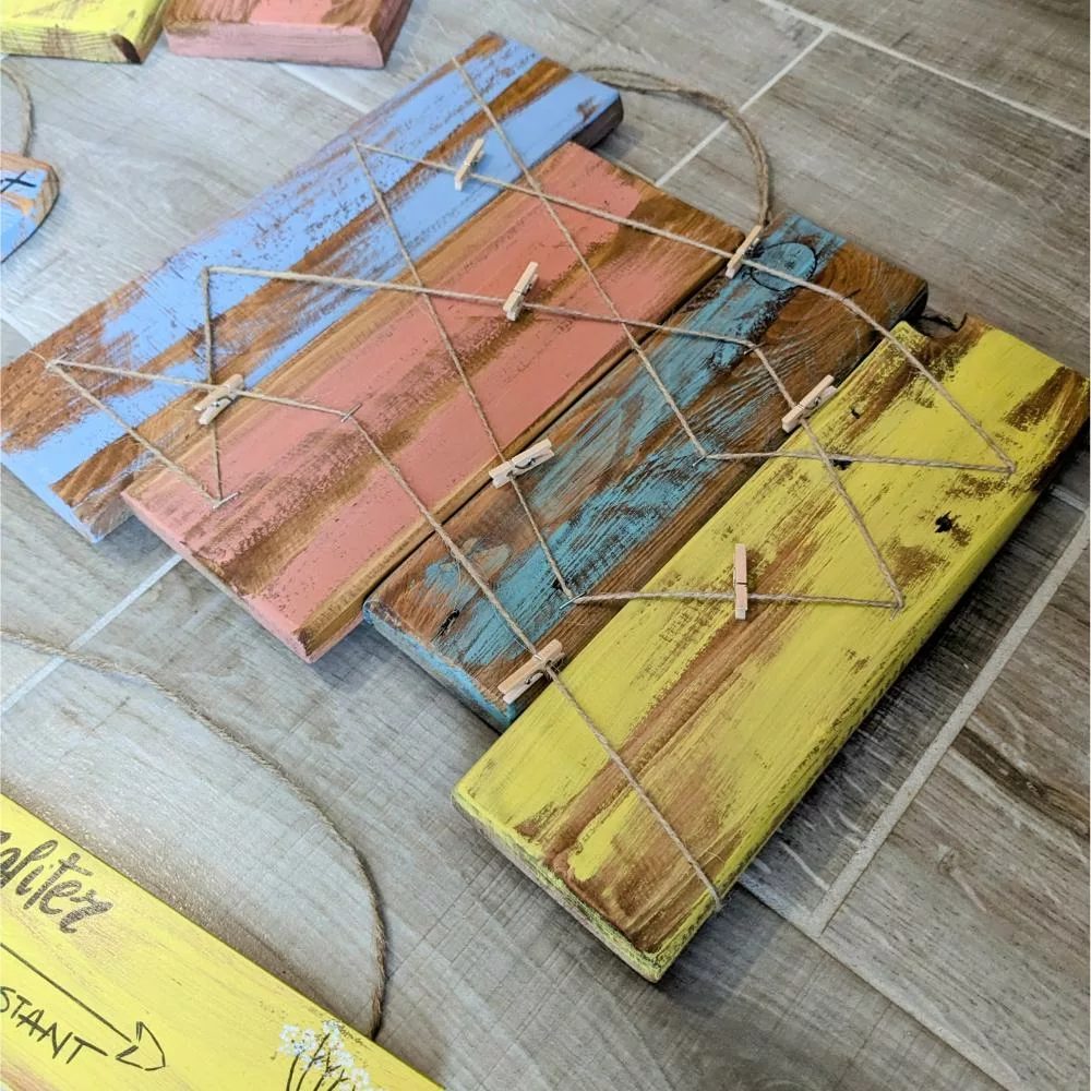 Pêle-mêle en bois brut et coloré avec fils croisés et pinces.